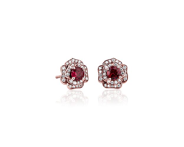 Stunning red rubies nestle at the heart of each of these delicate rose-shaped stud earrings crafted from 14k rose gold. The petals of each rose are elegantly set with delicate diamonds for a double halo that surrounds each ruby.