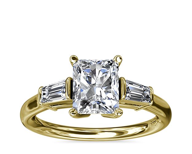 A timeless symbol of love and beauty, this 18k yellow engagement ring marries Art Deco-inspired style with pure elegance as twin tapered baguette diamonds frame a center stone casting their everlasting light in every direction.