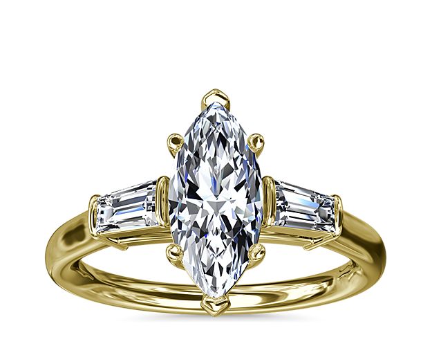 A timeless symbol of love and beauty, this 18k yellow engagement ring marries Art Deco-inspired style with pure elegance as twin tapered baguette diamonds frame a center stone casting their everlasting light in every direction.